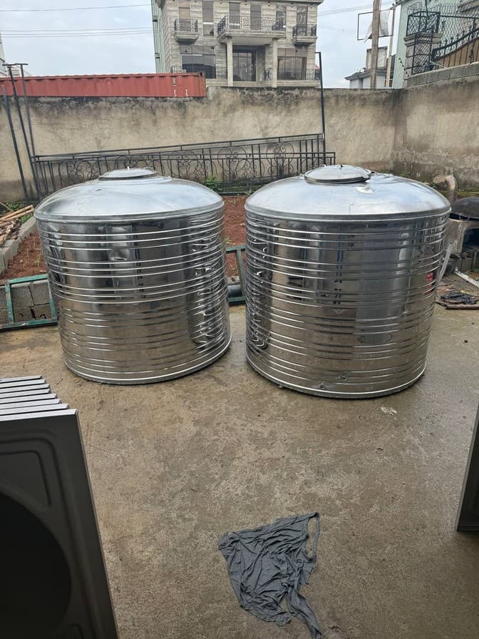 Pair of cylindrical stainless water tanks on a concrete pad